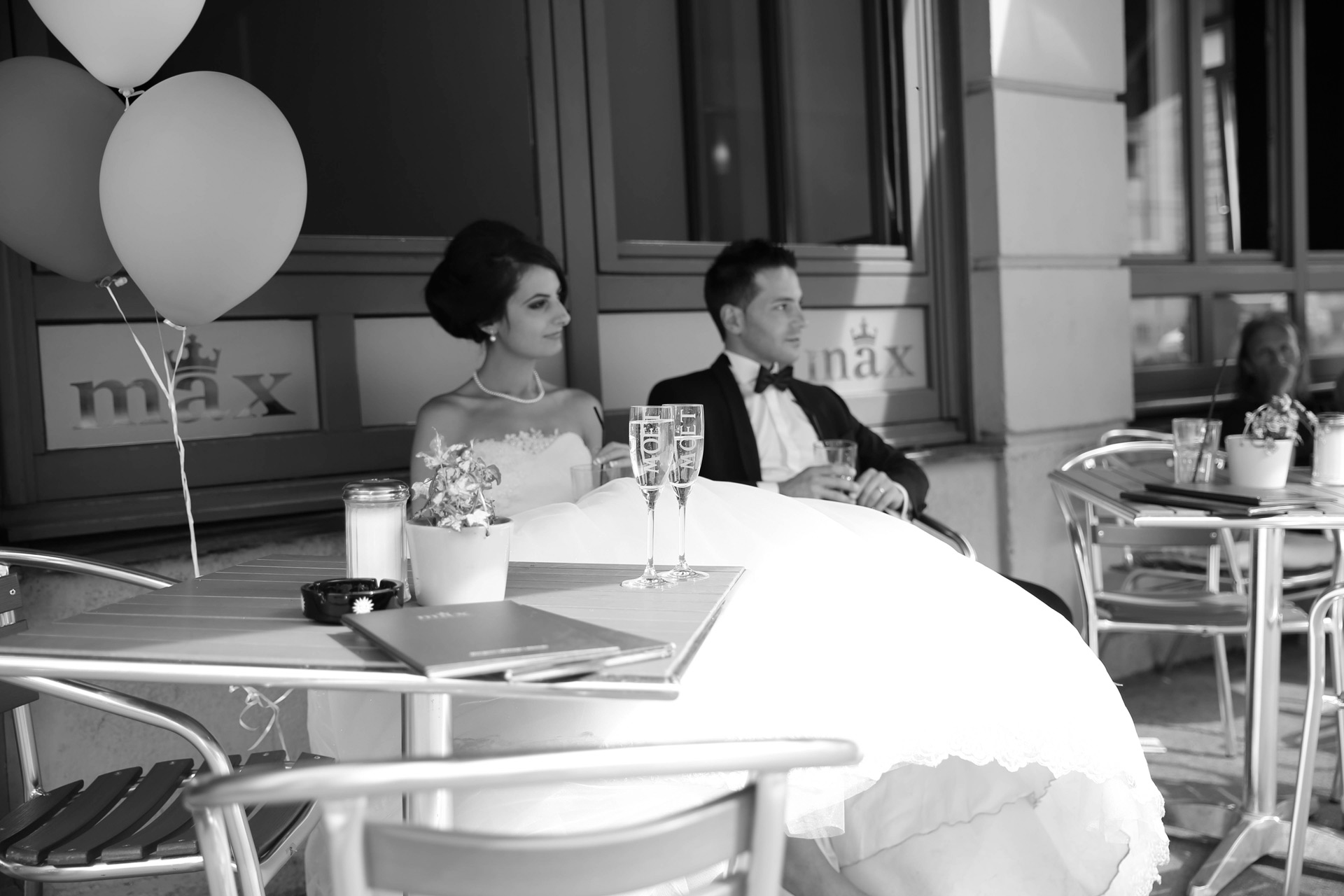 Hochzeit in der Maxstraße Augsburg, Braut sitzt drausse nim Cafe Max mit Champagner